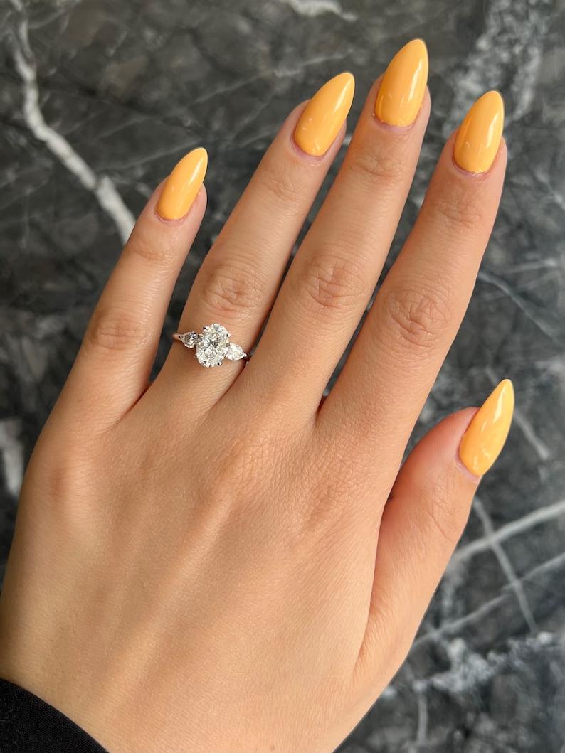 Certified oval cut diamond featured in three stone engagement ring