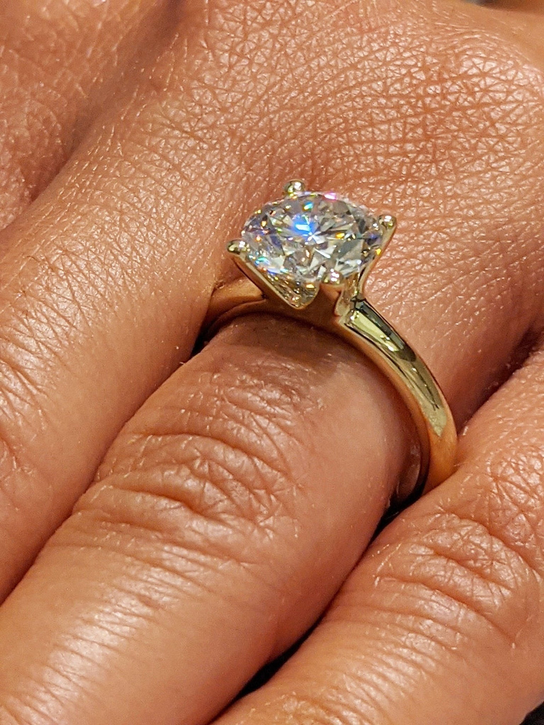 Lifestyle shot of round solitaire diamond ring on hand