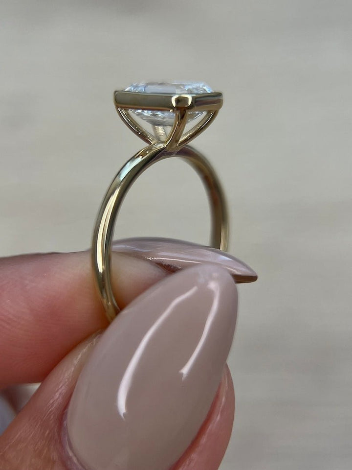 Emerald bezel diamond ring displayed on jewelry stand