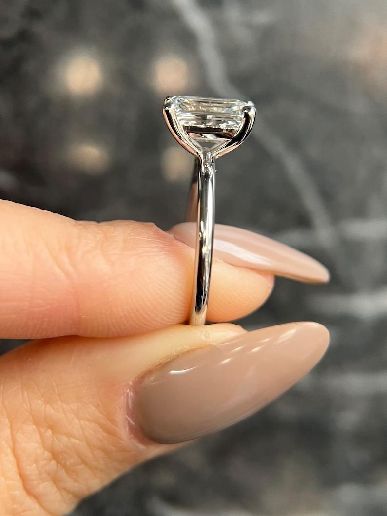 Emerald cut engagement ring shown with authenticity certificate