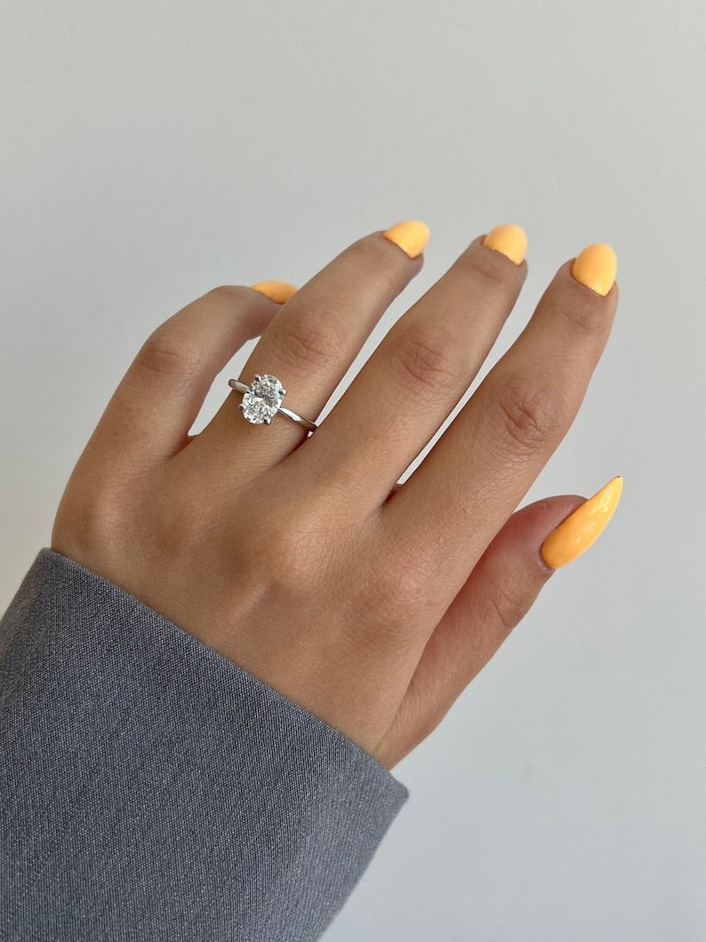 Oval hidden halo engagement ring offered in gold and platinum
