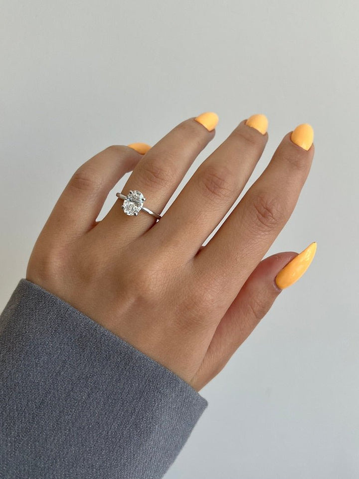 Oval hidden halo engagement ring offered in gold and platinum