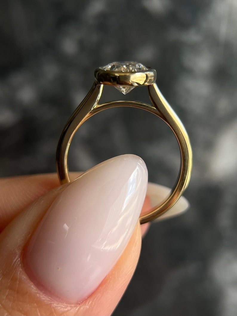 Oval bezel diamond ring displayed on jewelry stand