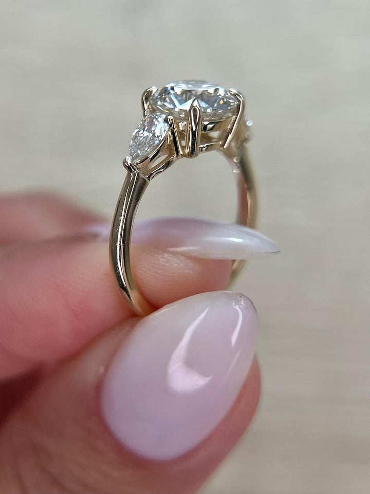 Detailed close-up of round three stone diamond engagement ring