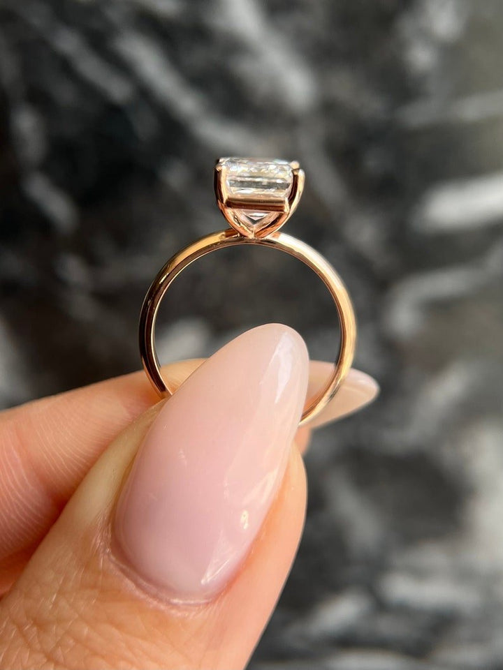 Emerald solitaire diamond ring displayed on jewelry stand