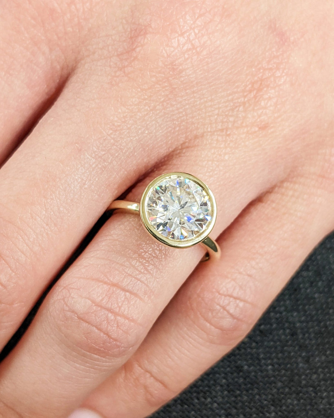 Round bezel engagement ring shown on hand for true-to-life sizing