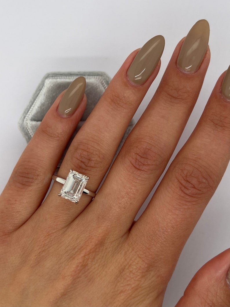Emerald hidden halo engagement ring shown on hand for true-to-life sizing
