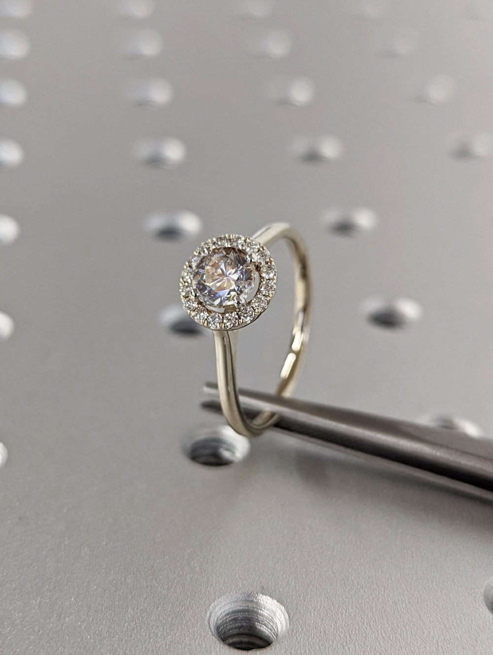 Close-up of round cut center diamond in halo engagement ring