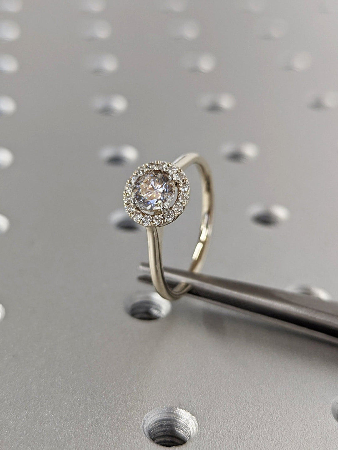 Close-up of round cut center diamond in halo engagement ring
