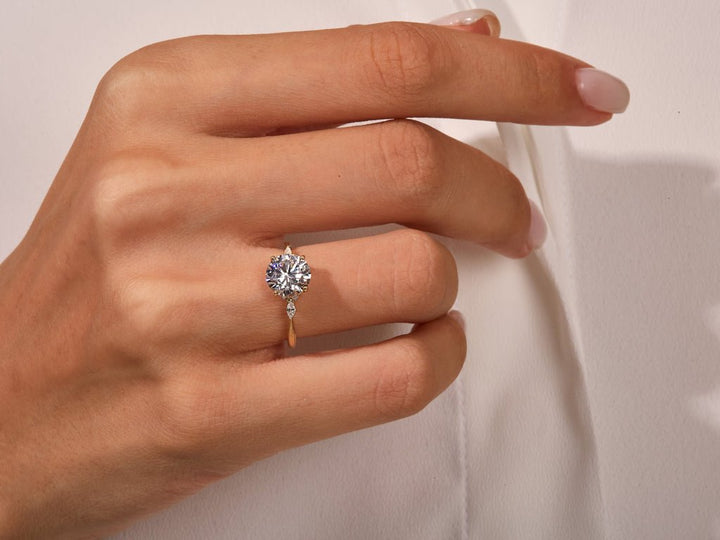 Lifestyle shot of round three stone diamond ring on hand