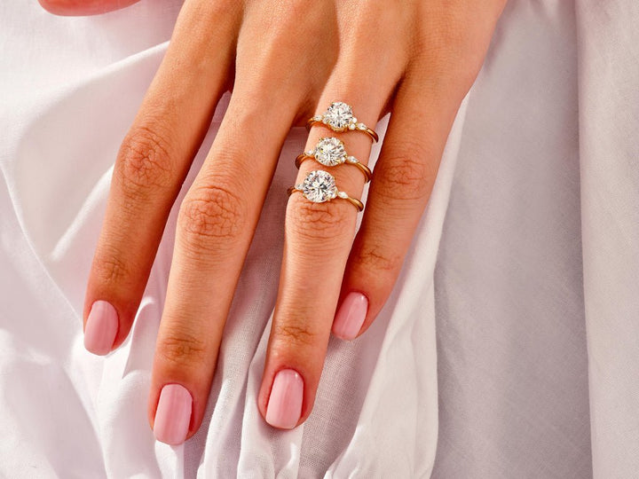 Round cut three stone engagement ring shown in real-life wear