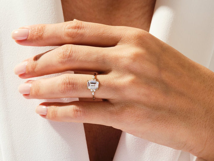 Emerald cluster engagement ring shown on hand for true-to-life sizing