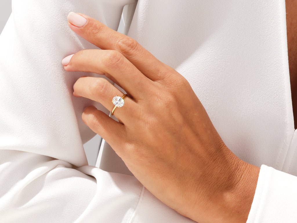 Oval solitaire engagement ring shown on hand for true-to-life sizing