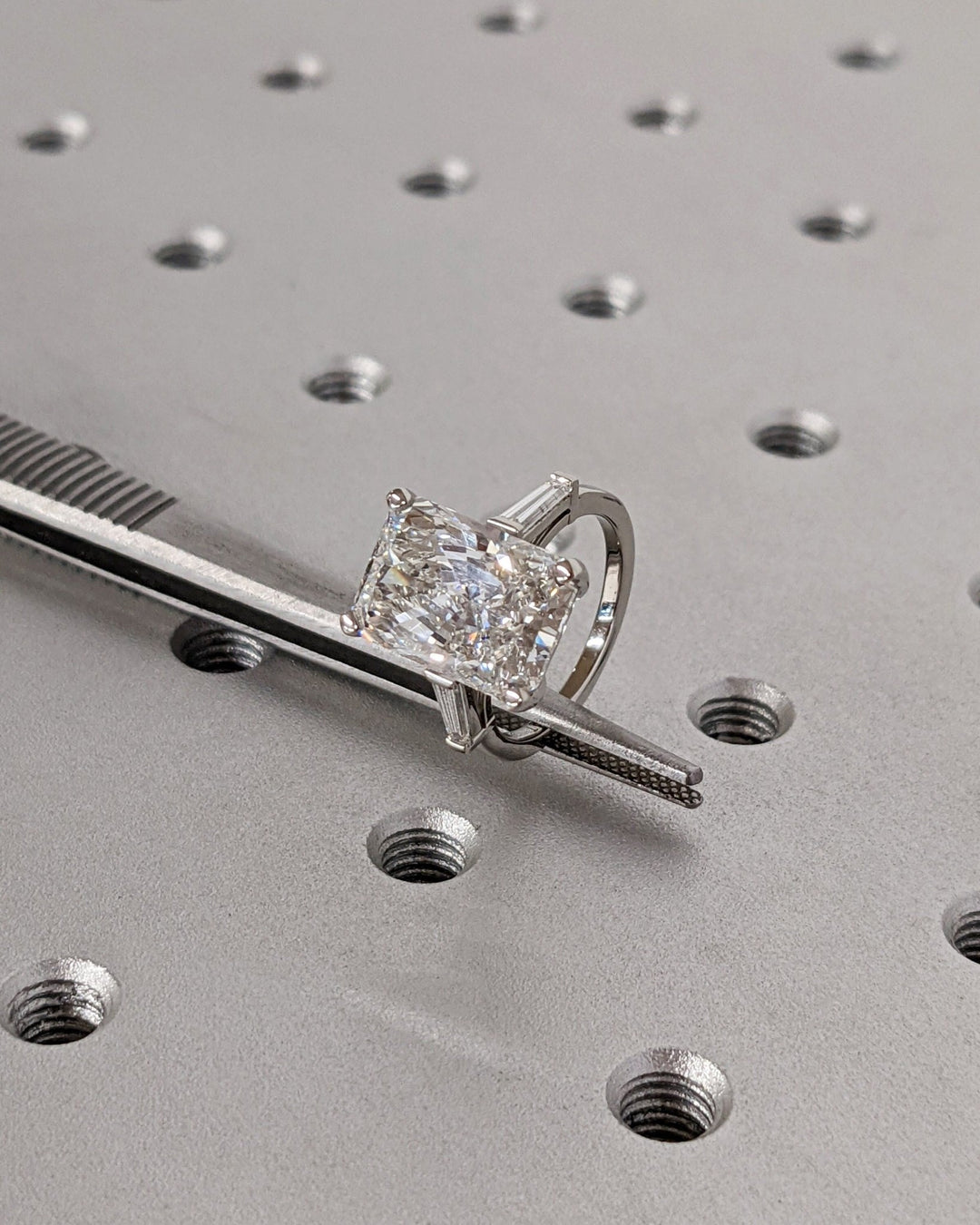 Close-up of radiant cut center diamond in three stone engagement ring