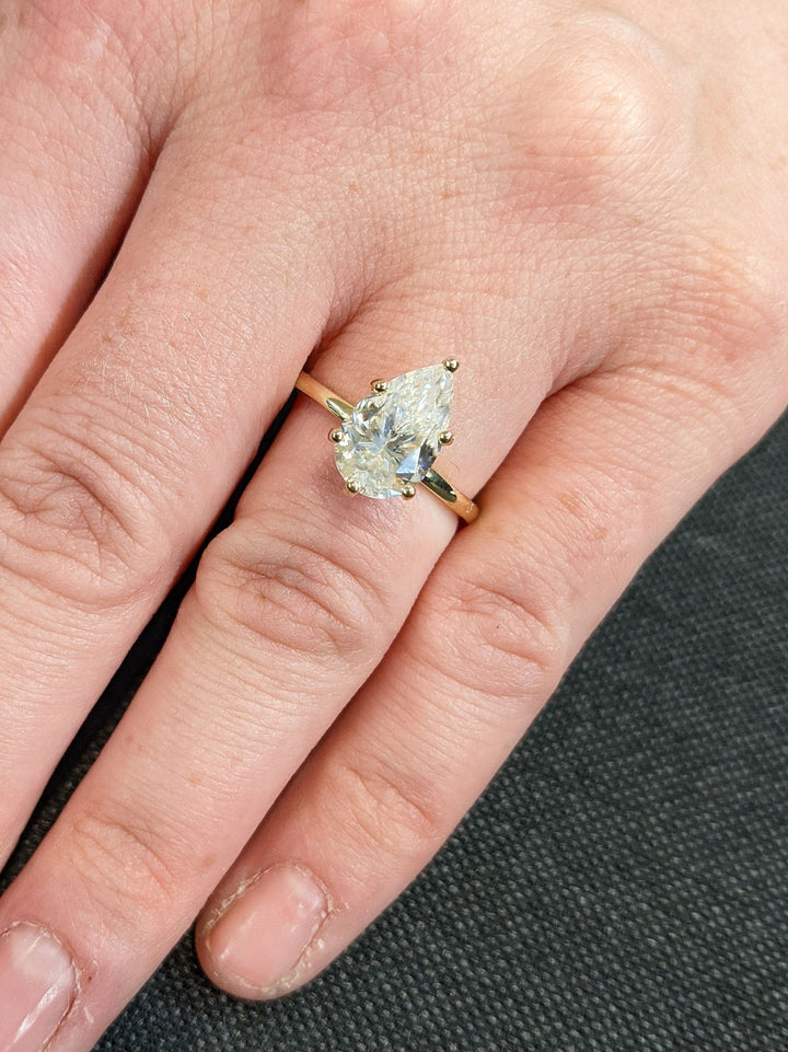 Close-up of pear cut center diamond in hidden halo engagement ring