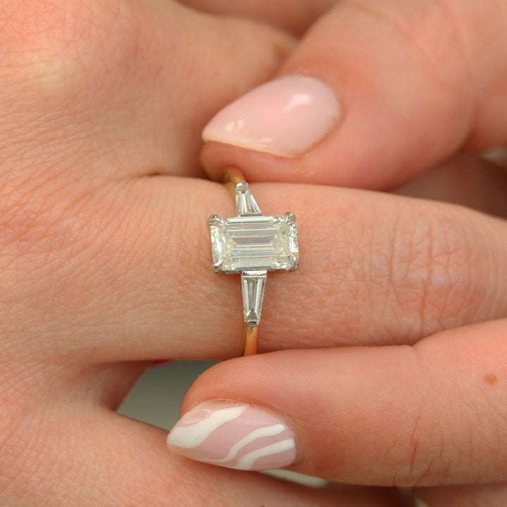Certified emerald cut diamond featured in three stone engagement ring