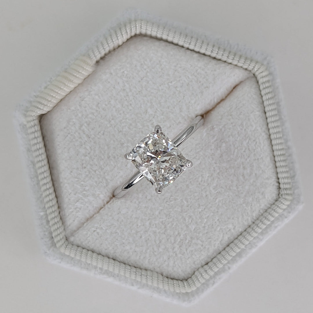 Cushion cut engagement ring shown with authenticity certificate