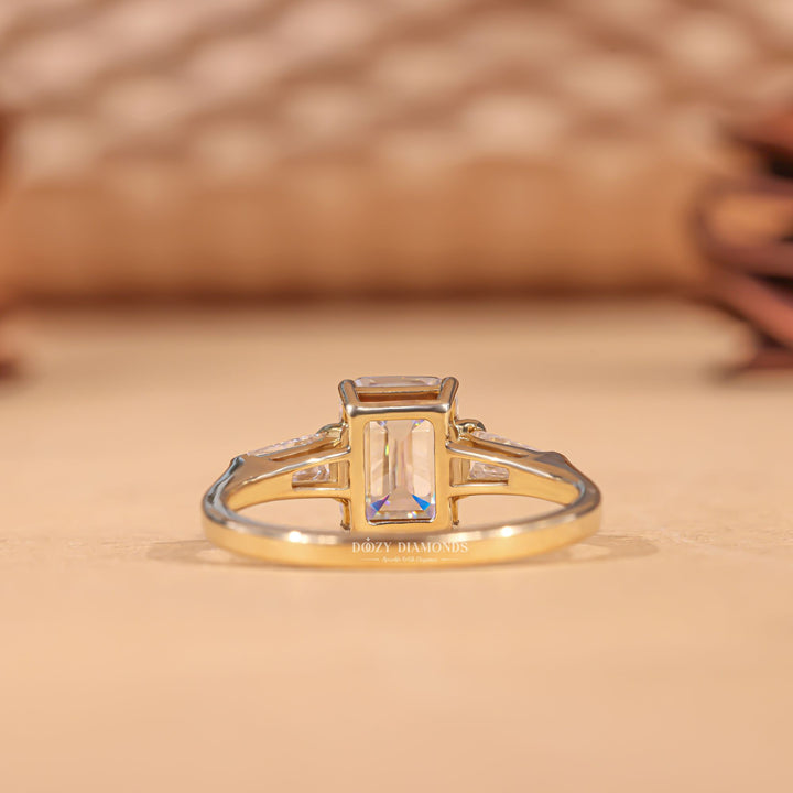 Close-up of emerald cut center diamond in three stone engagement ring