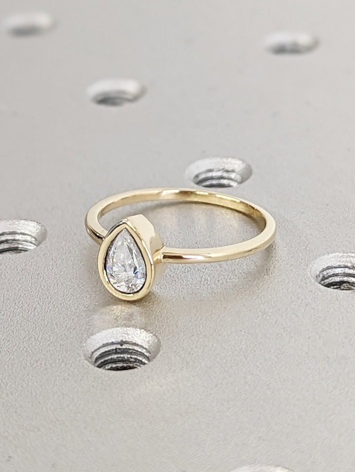 Pear bezel engagement ring finished in polished solid gold