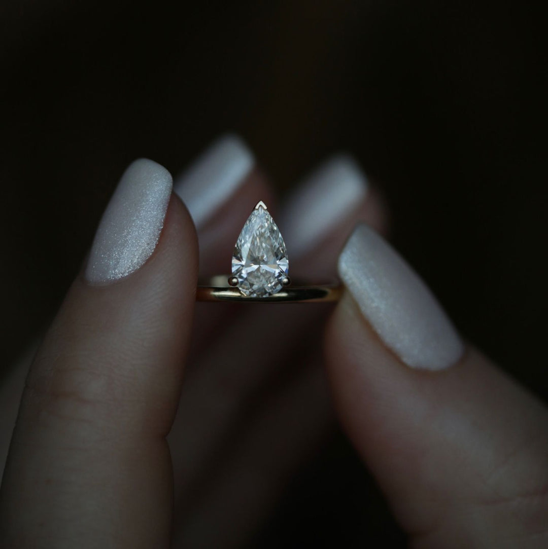 Pear solitaire diamond ring displayed on jewelry stand