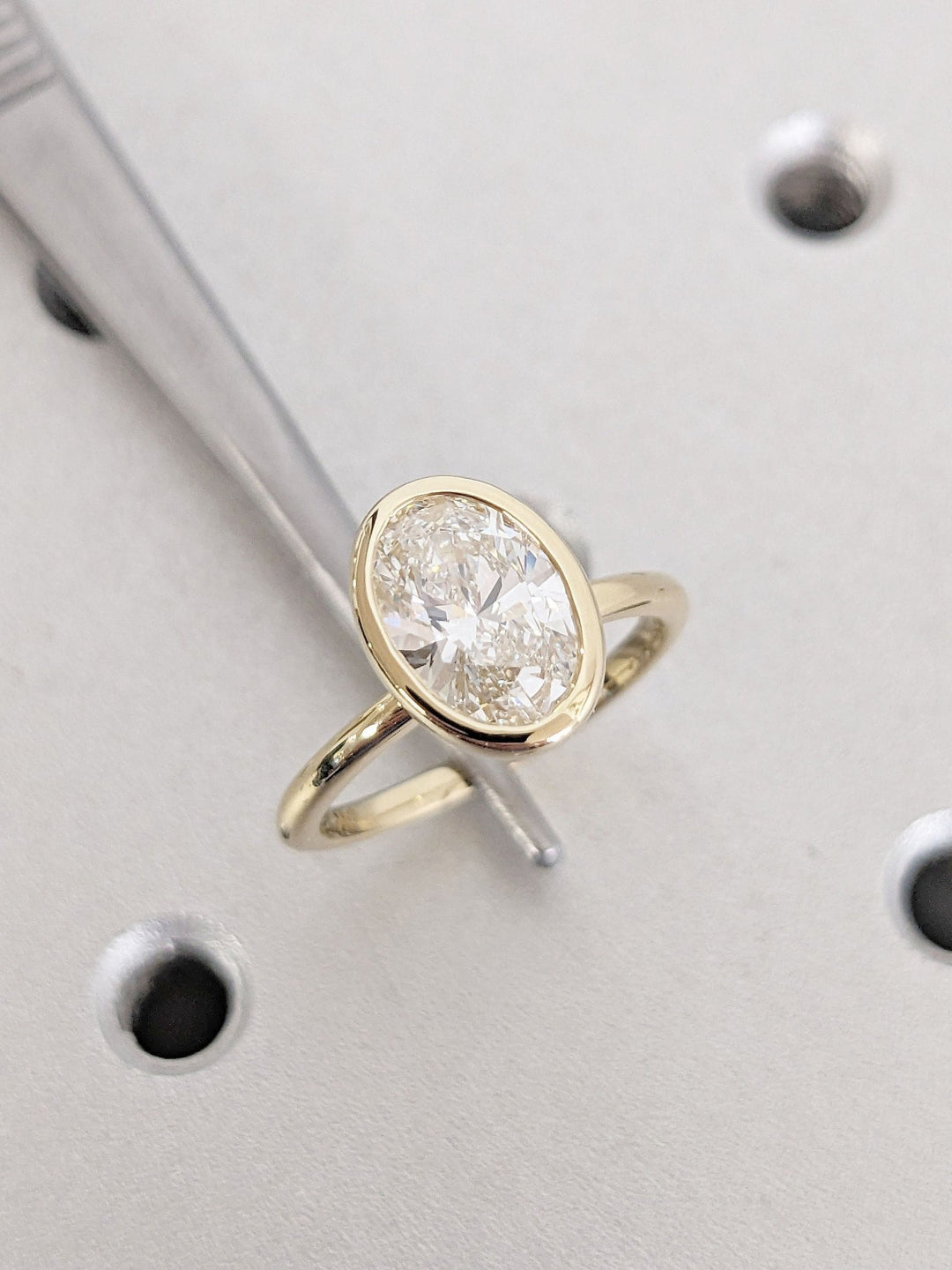 Close-up of oval cut center diamond in bezel engagement ring