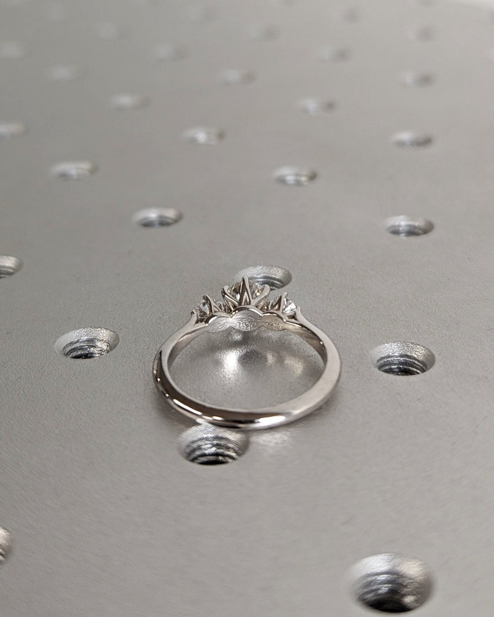Round three stone diamond ring displayed on jewelry stand