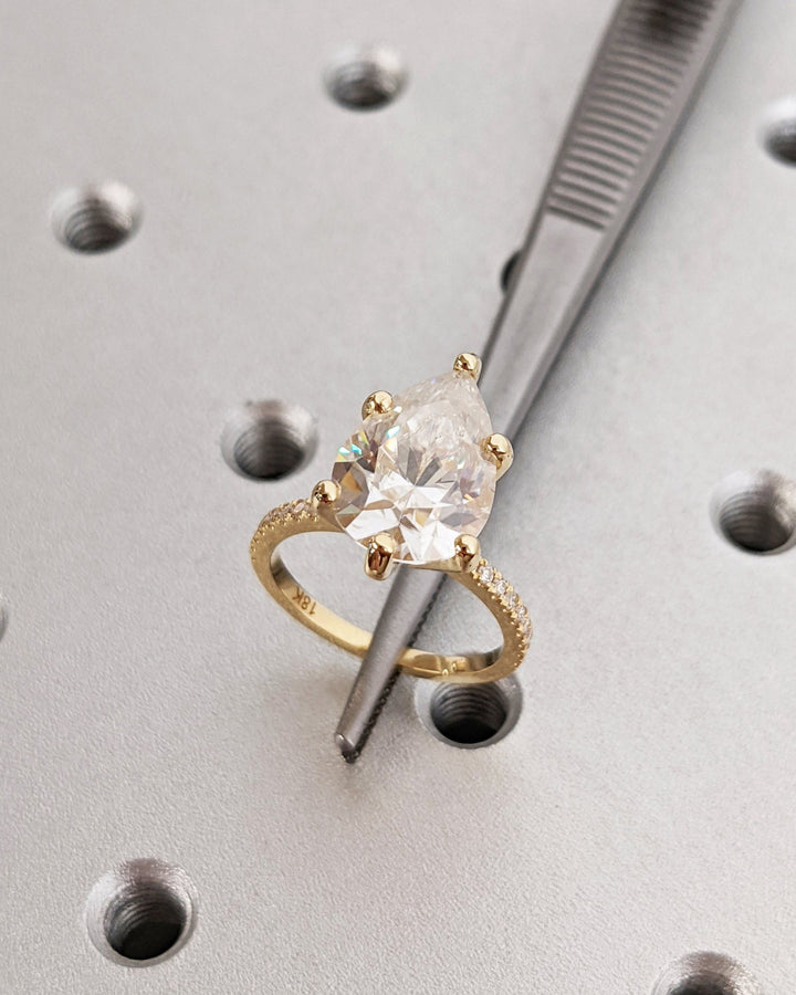 Pear hidden halo diamond ring displayed on jewelry stand