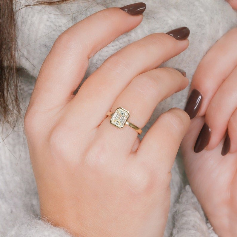Emerald cut engagement ring shown with authenticity certificate