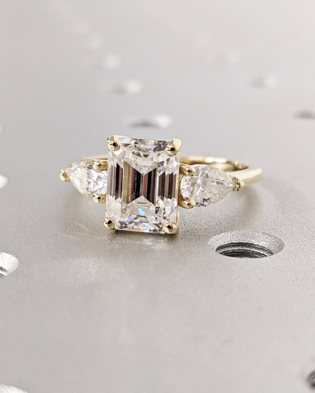 Detailed close-up of emerald three stone diamond engagement ring