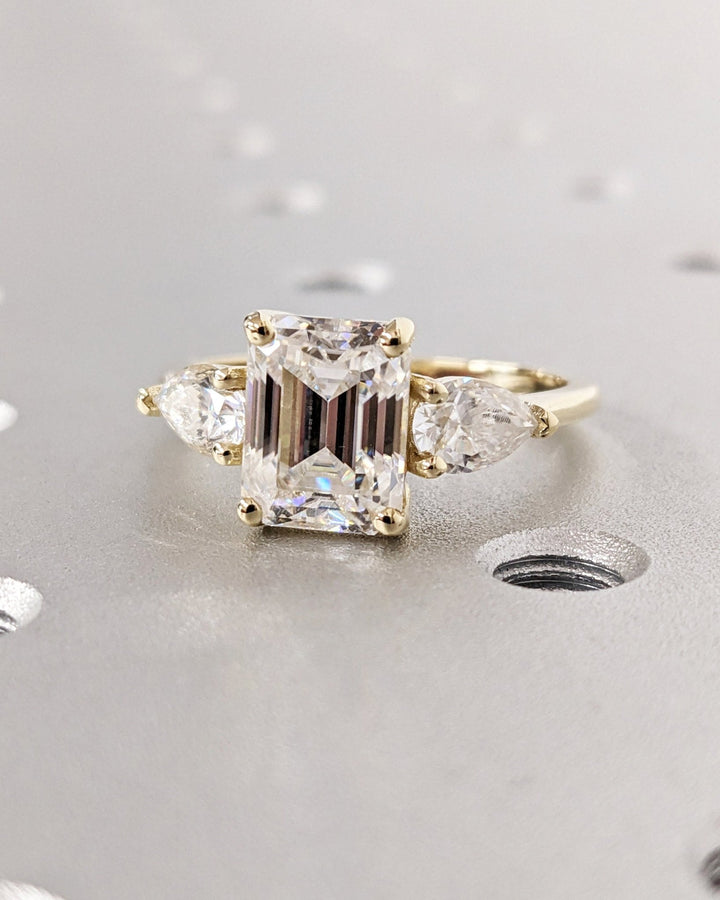 Detailed close-up of emerald three stone diamond engagement ring