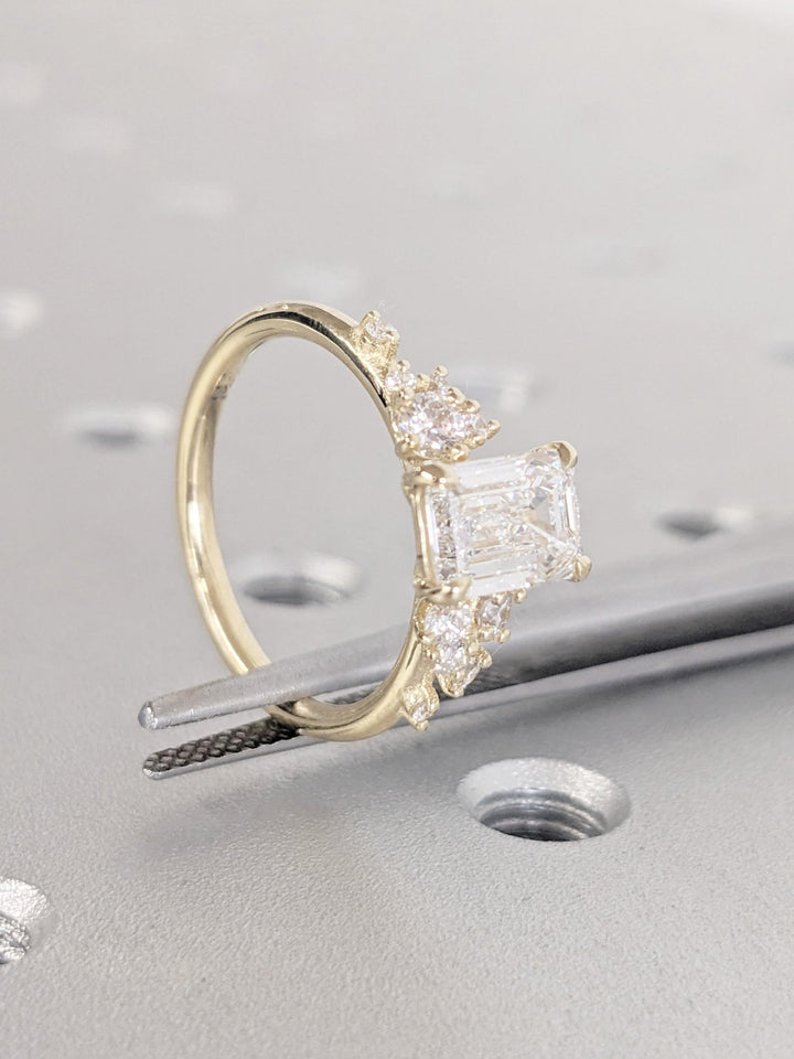 Emerald cluster diamond ring displayed on jewelry stand