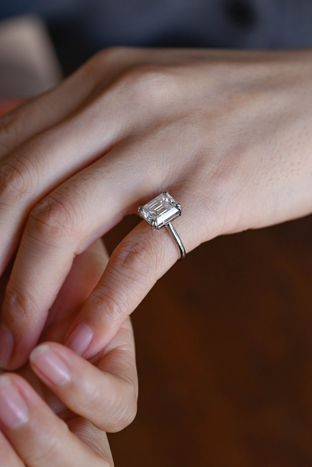 Emerald solitaire diamond ring displayed on jewelry stand