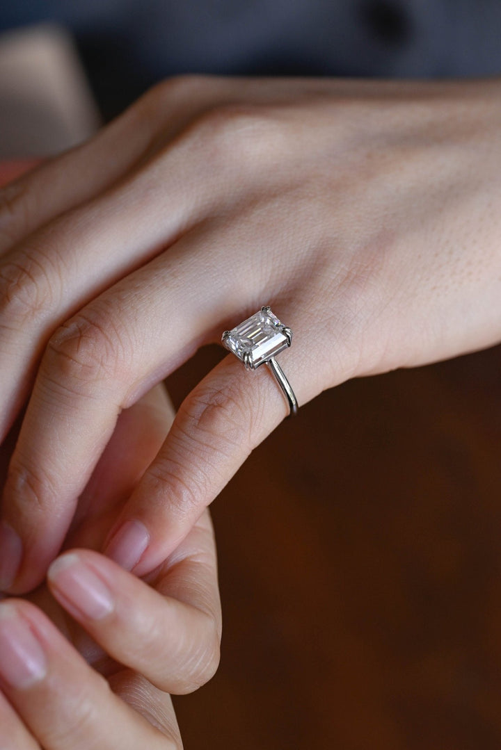Emerald solitaire diamond ring displayed on jewelry stand