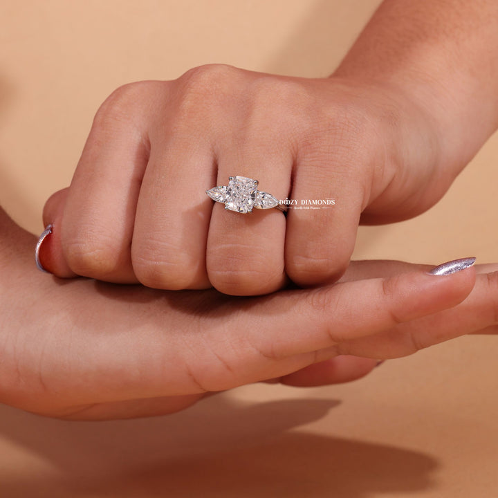 Lifestyle shot of cushion three stone diamond ring on hand