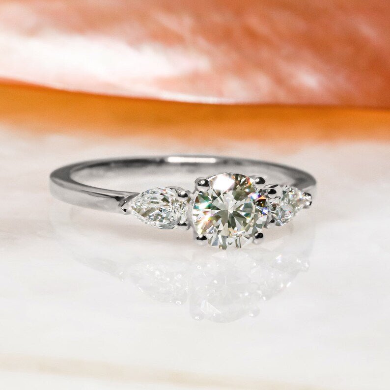 Certified round cut diamond featured in three stone engagement ring