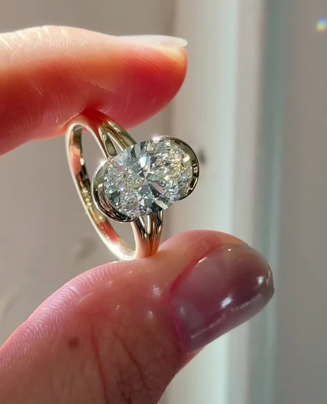 Oval bezel diamond ring displayed on jewelry stand