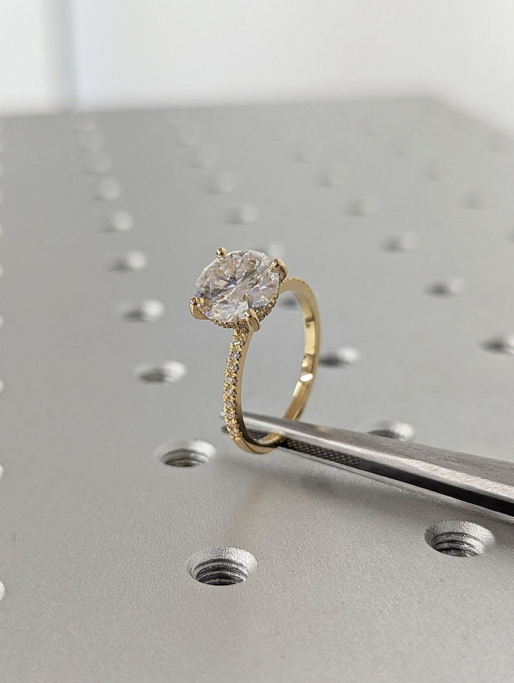 Round hidden halo engagement ring photographed in natural light