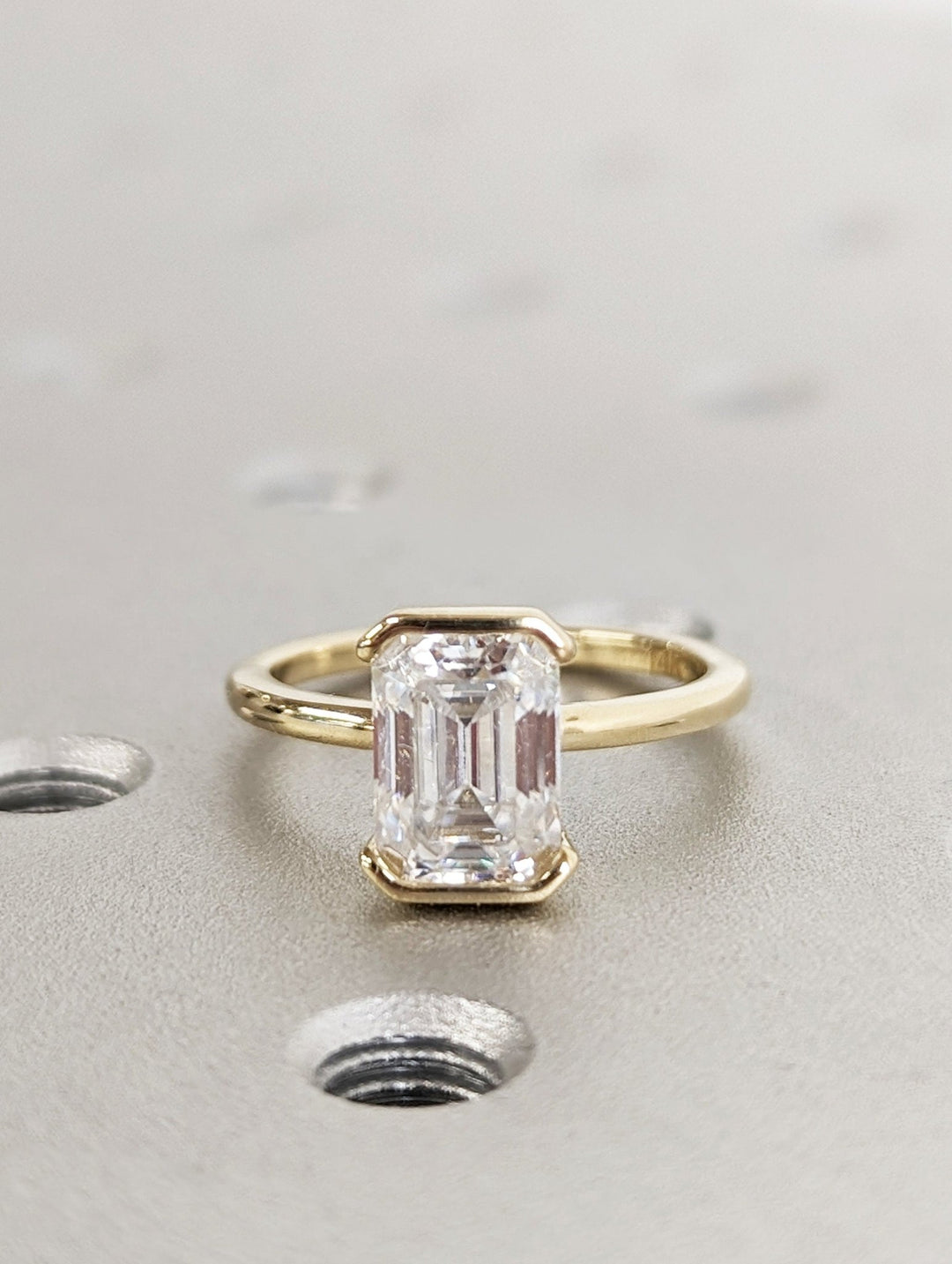 Certified emerald cut diamond featured in bezel engagement ring