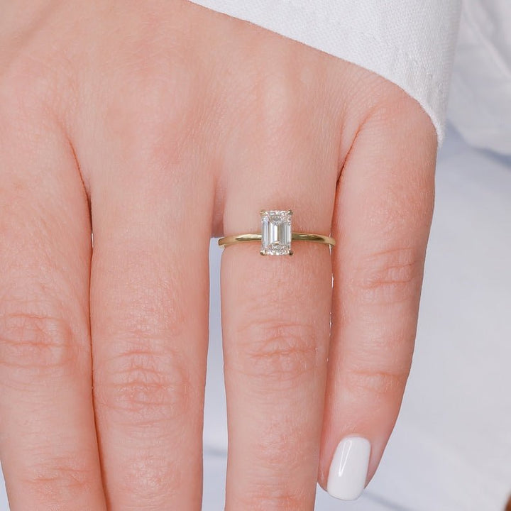 Emerald hidden halo engagement ring shown on hand for true-to-life sizing