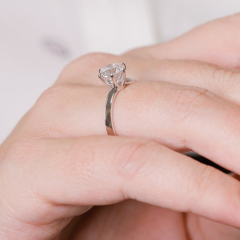 Round solitaire diamond ring displayed on jewelry stand
