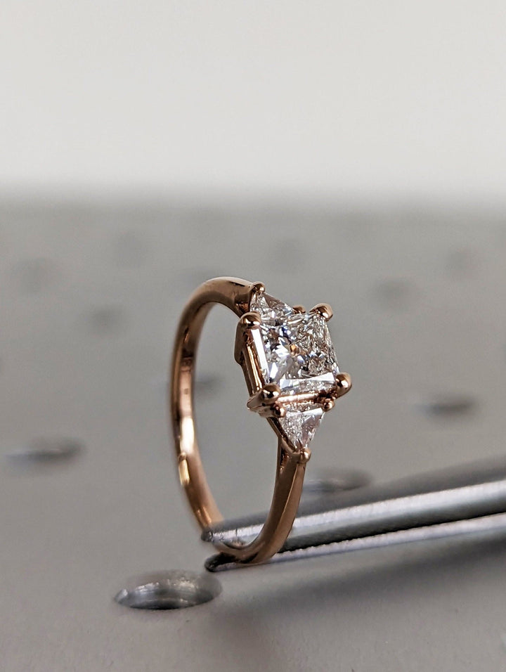Angled view of princess cut diamond in three stone setting