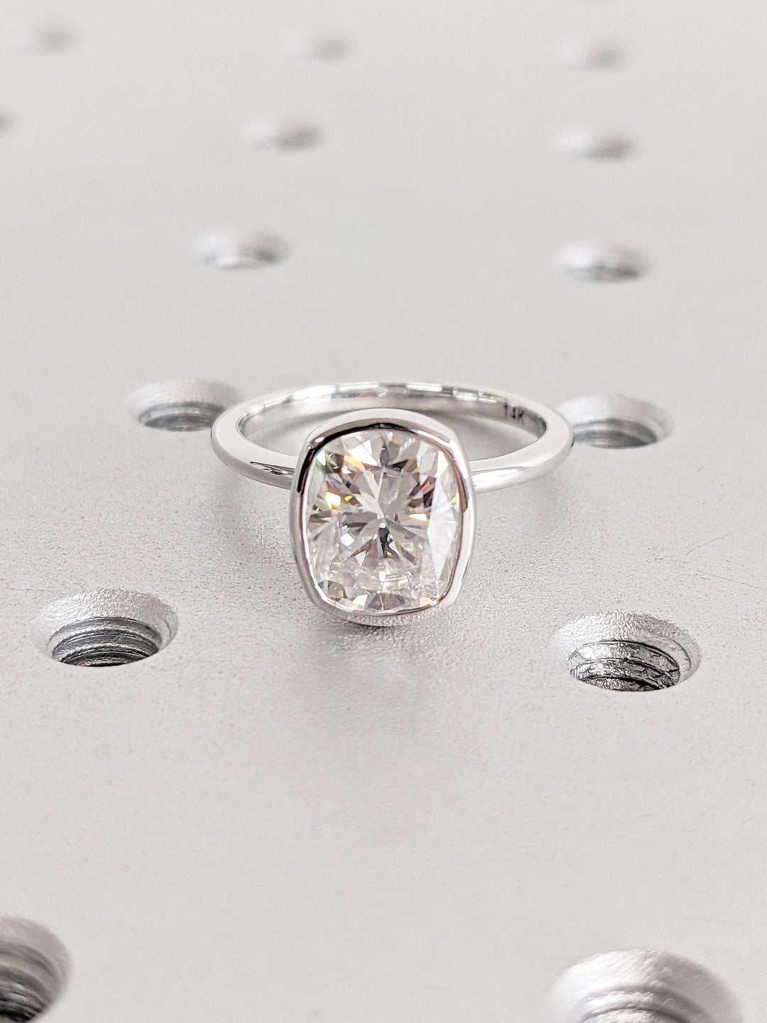 Cushion bezel diamond ring displayed on jewelry stand