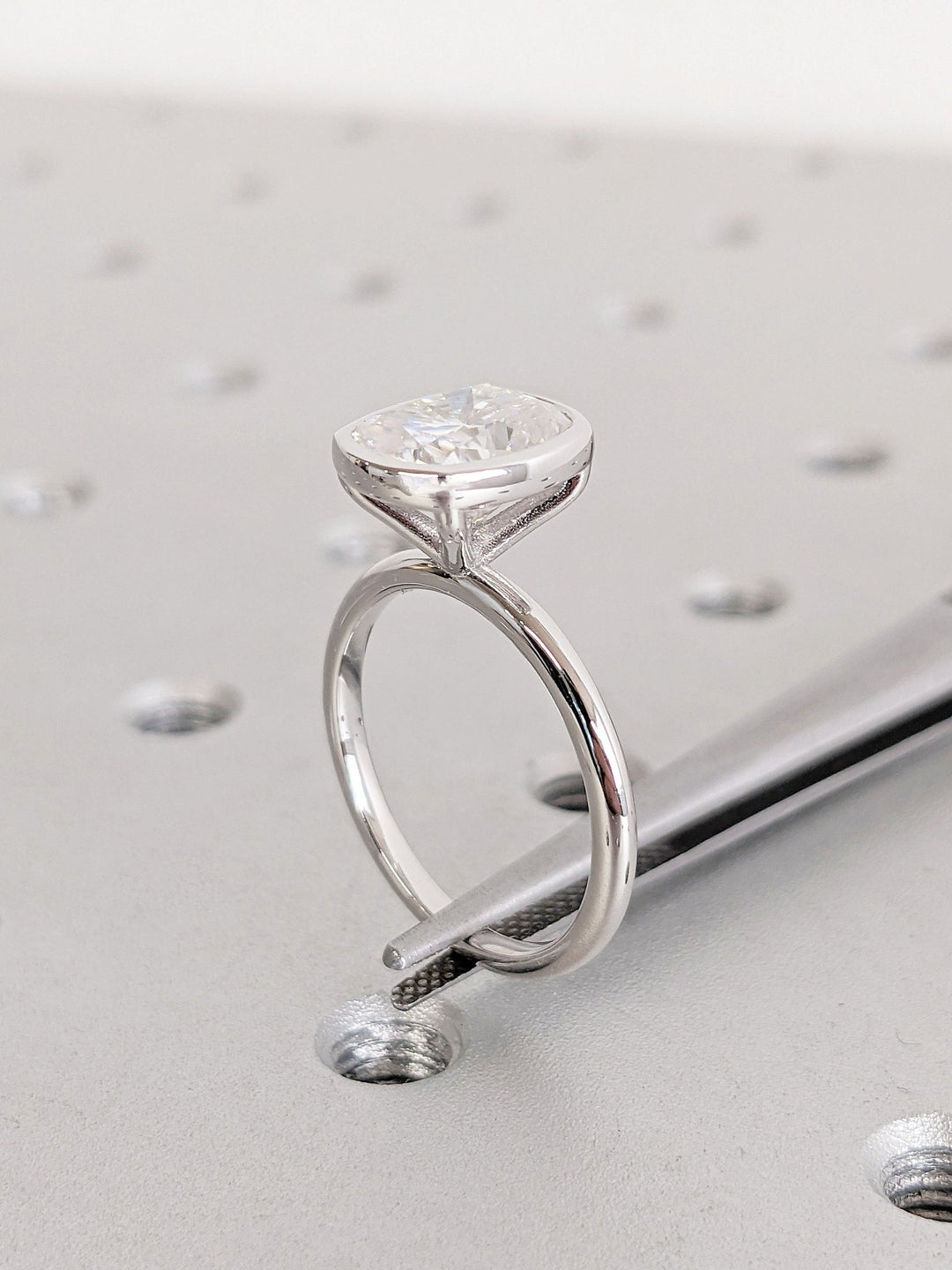 Close-up of cushion cut center diamond in bezel engagement ring