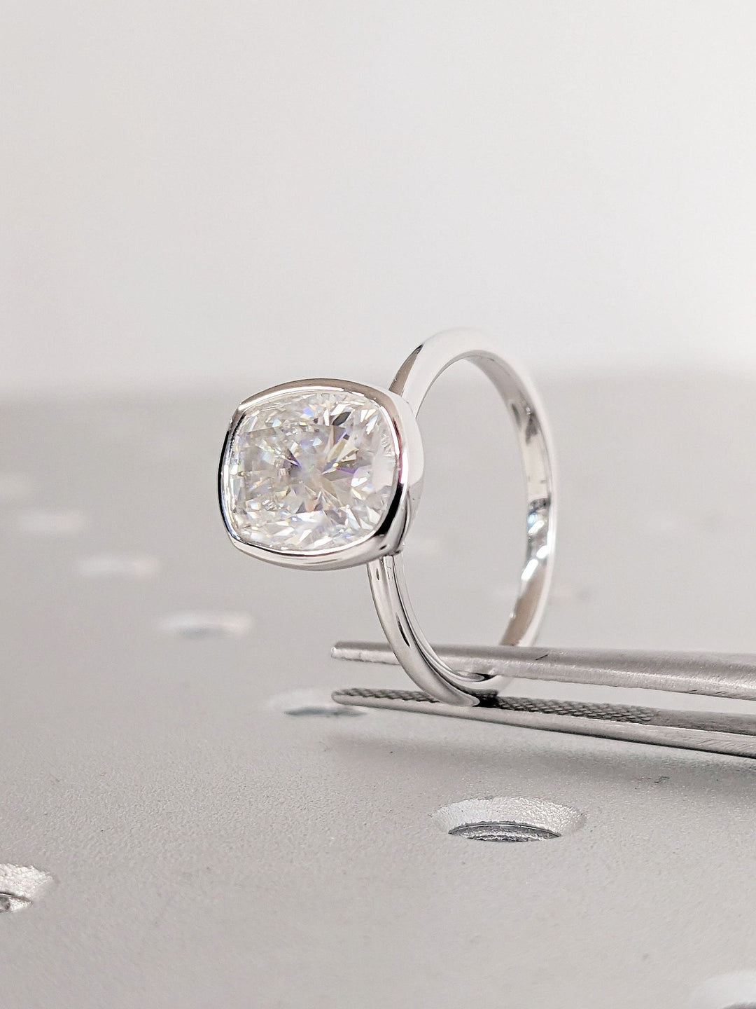 Macro shot of cushion cut diamond facets in bezel ring setting