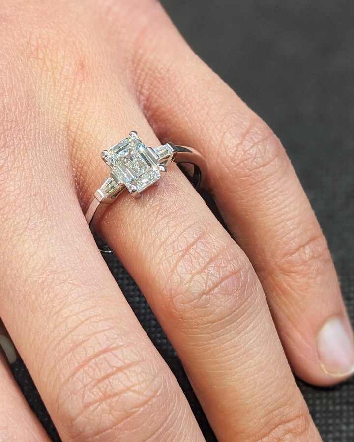 Emerald three stone engagement ring close-up highlighting diamond sparkle