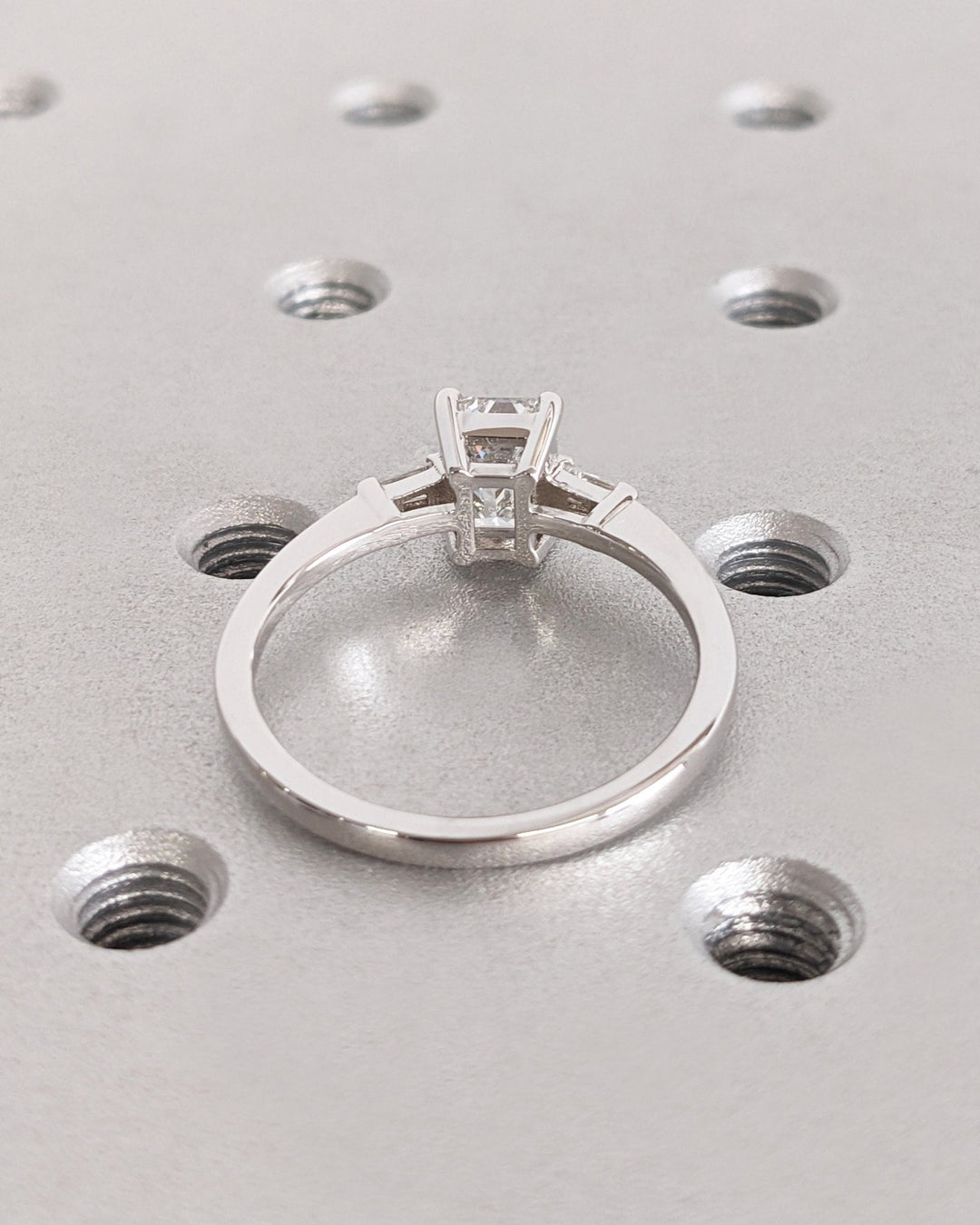 Angled view of emerald cut diamond in three stone setting