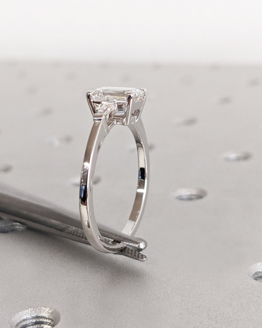 Close-up of emerald cut center diamond in three stone engagement ring