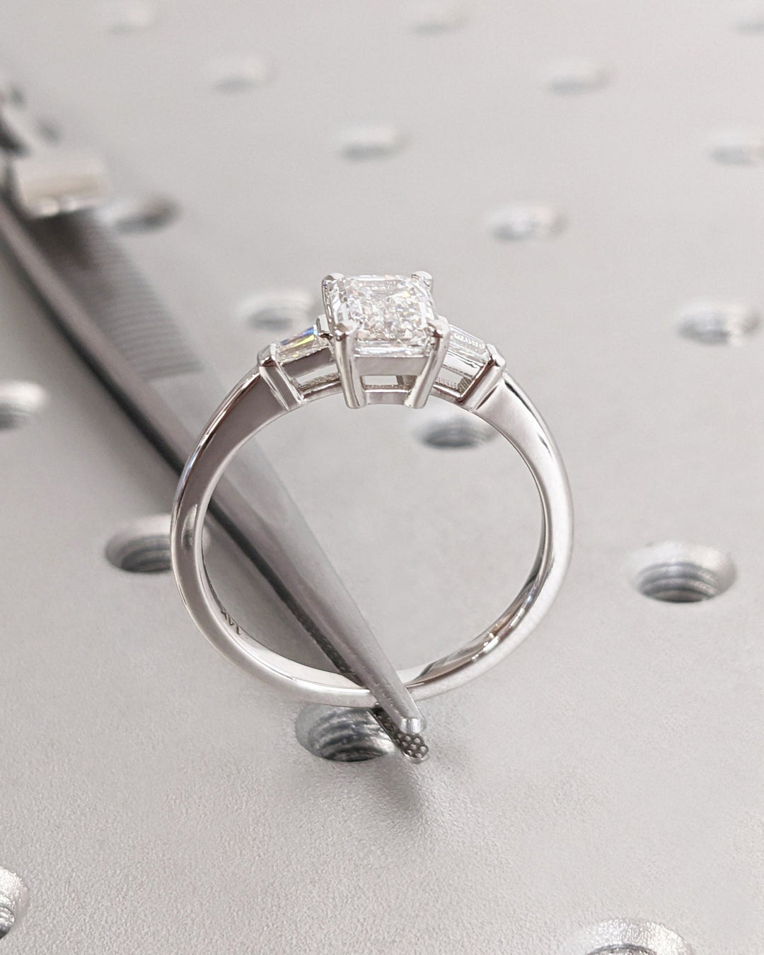 Macro shot of emerald cut diamond facets in three stone ring setting