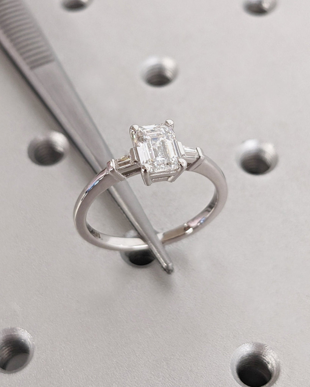 Detailed close-up of emerald three stone diamond engagement ring
