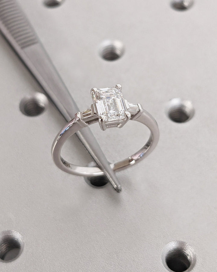Detailed close-up of emerald three stone diamond engagement ring